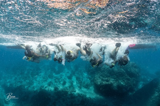 Group of divers backrolling into the water